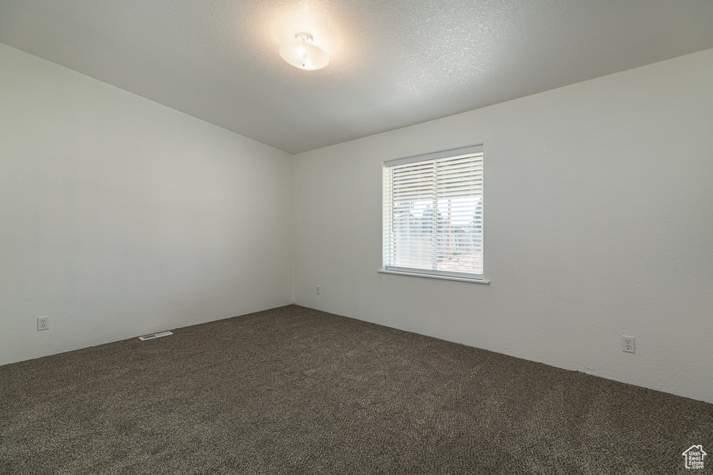 Unfurnished room featuring dark carpet and visible vents