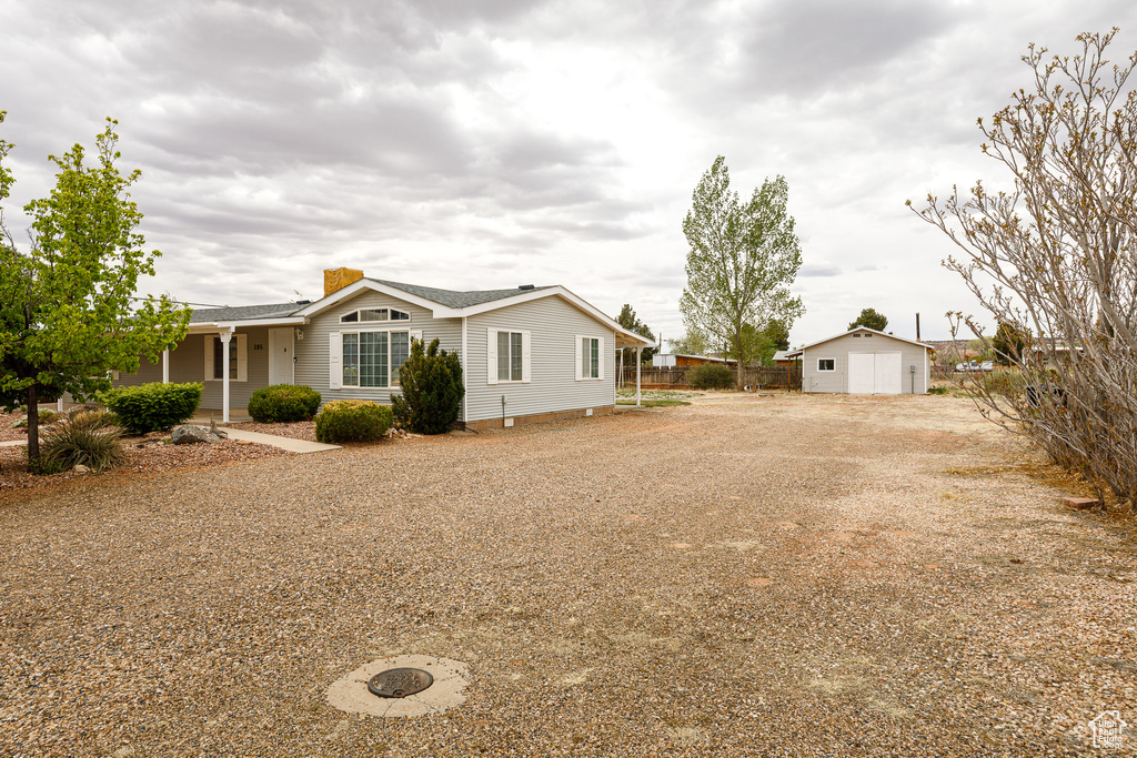 Exterior space featuring fence, a chimney, an outdoor structure, and roof with shingles