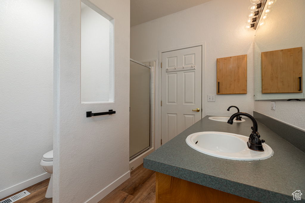 Full bathroom featuring visible vents, wood finished floors, toilet, a sink, and a stall shower