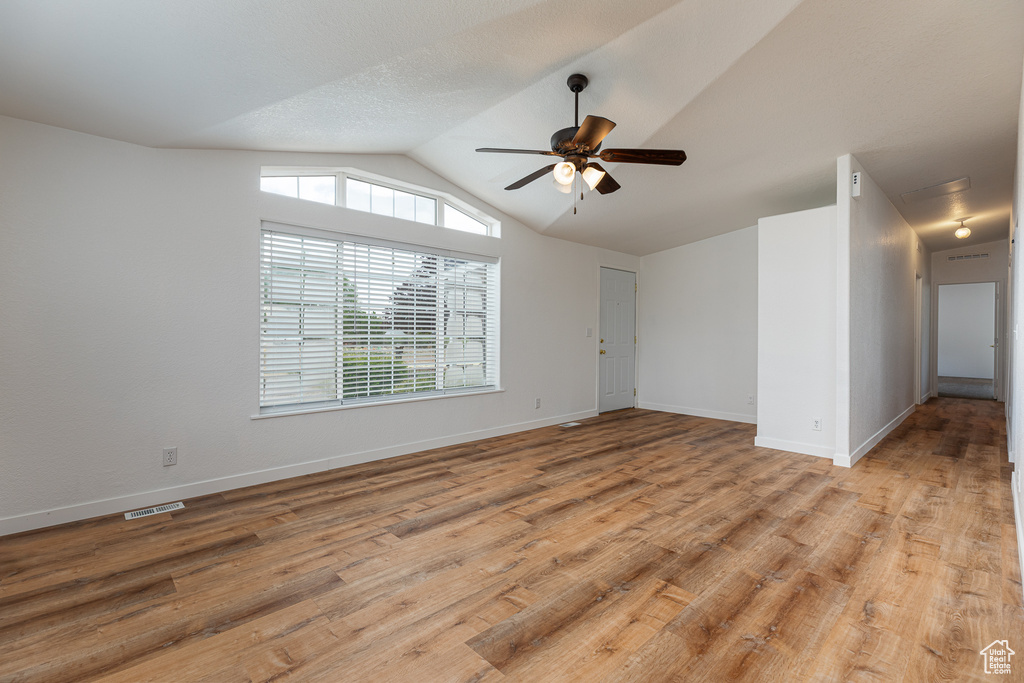 Unfurnished room featuring ceiling fan, visible vents, vaulted ceiling, baseboards, and light wood-style floors