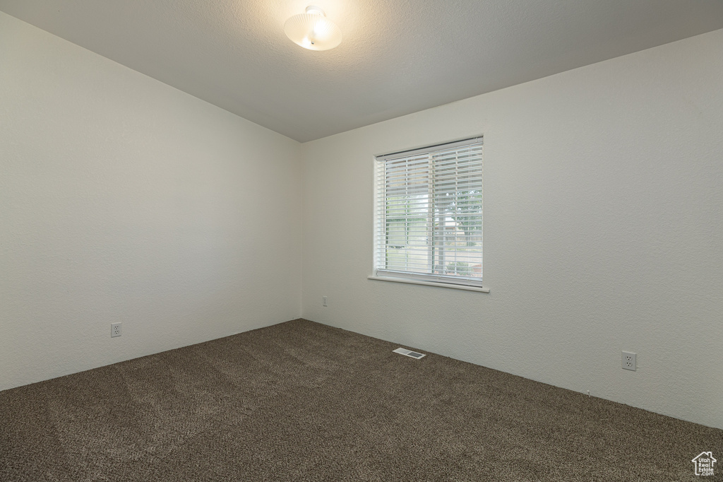 Spare room featuring dark carpet and visible vents