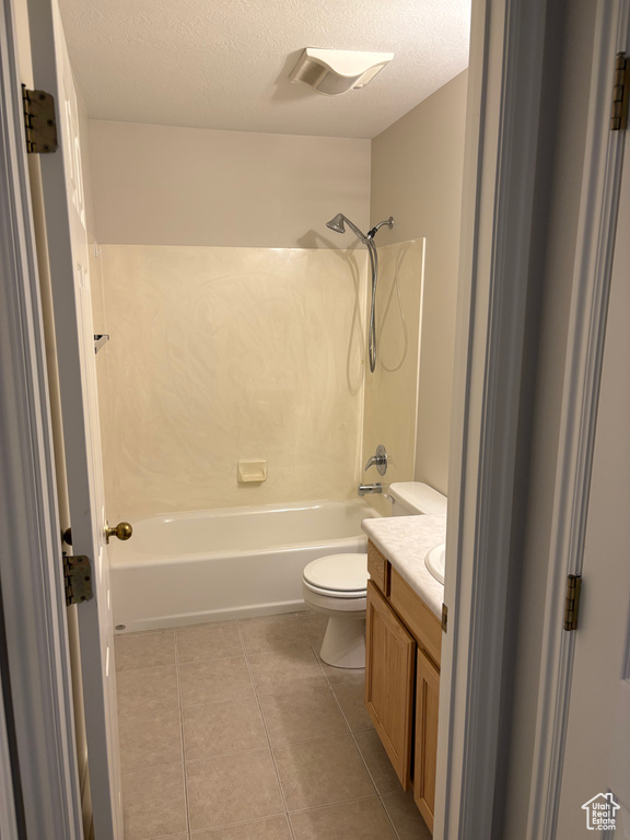 Bathroom with tile patterned flooring, vanity, toilet, a textured ceiling, and  shower combination