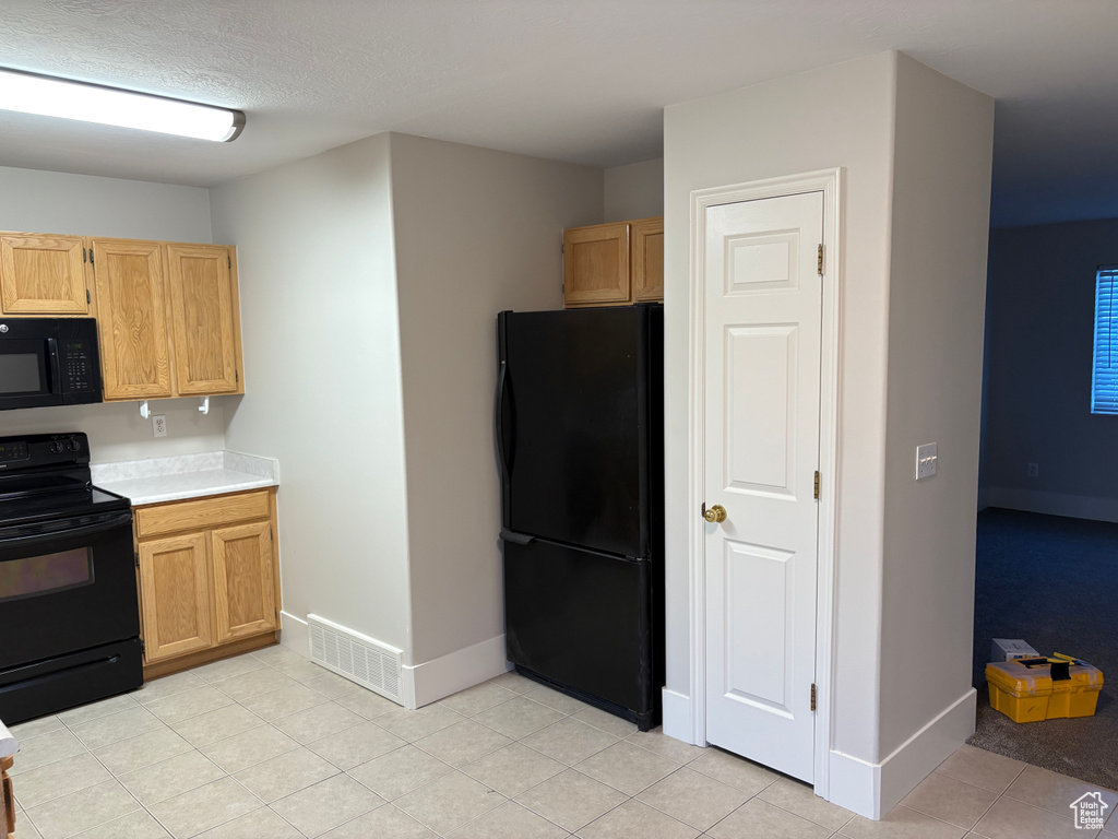 Kitchen featuring visible vents, baseboards, light countertops, light tile patterned floors, and black appliances