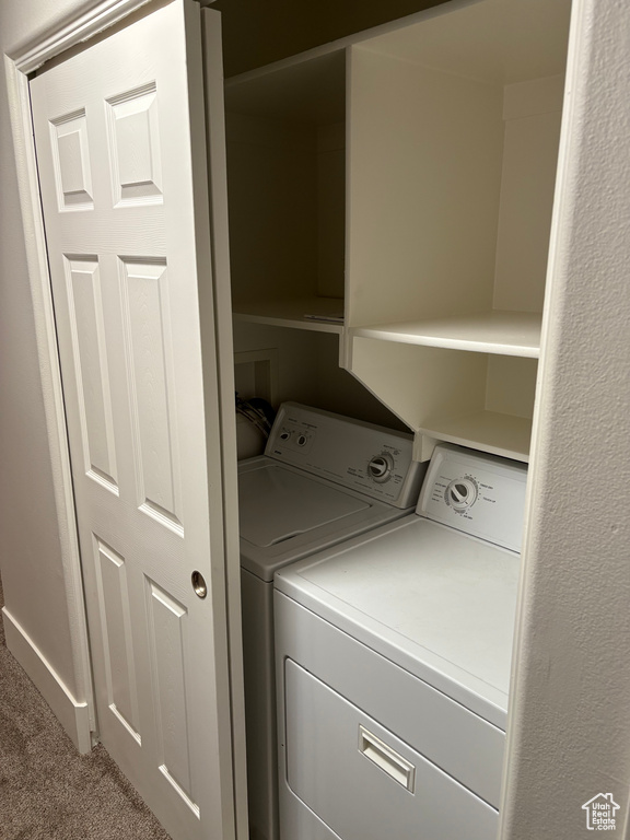Clothes washing area with carpet floors, laundry area, and washer and clothes dryer