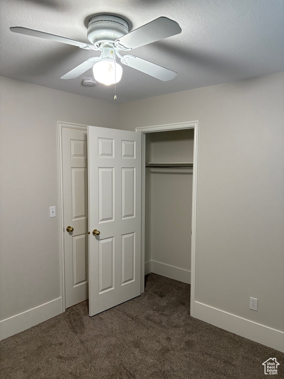 Unfurnished bedroom featuring a ceiling fan, baseboards, dark carpet, and a closet