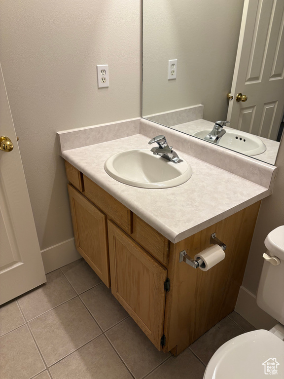 Half bathroom with vanity, tile patterned flooring, and toilet