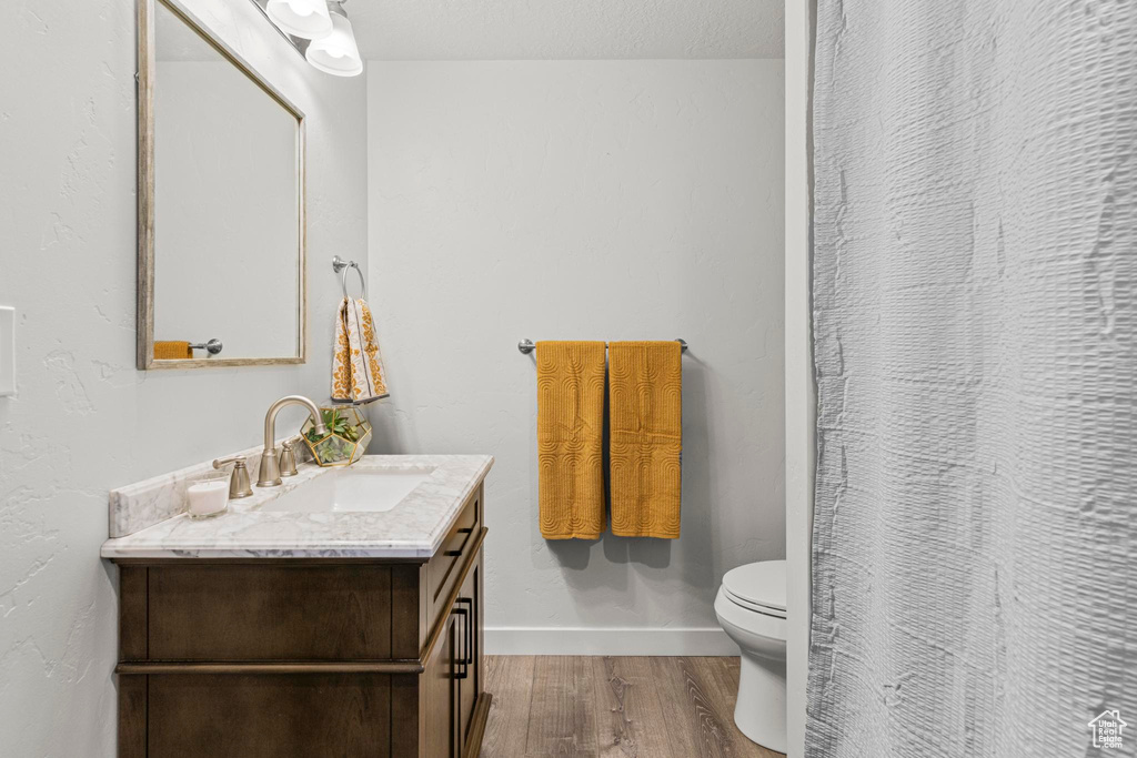 Bathroom with vanity, toilet, baseboards, wood finished floors, and a shower with curtain