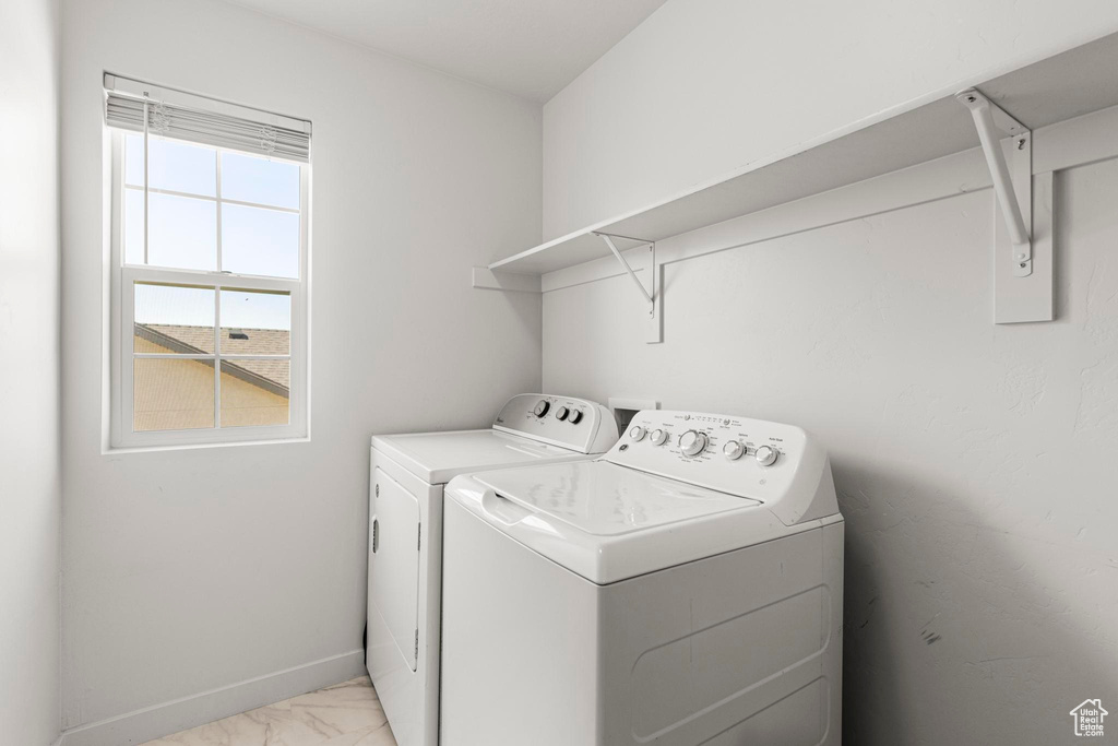 Washroom featuring laundry area, baseboards, marble finish floor, and washing machine and dryer