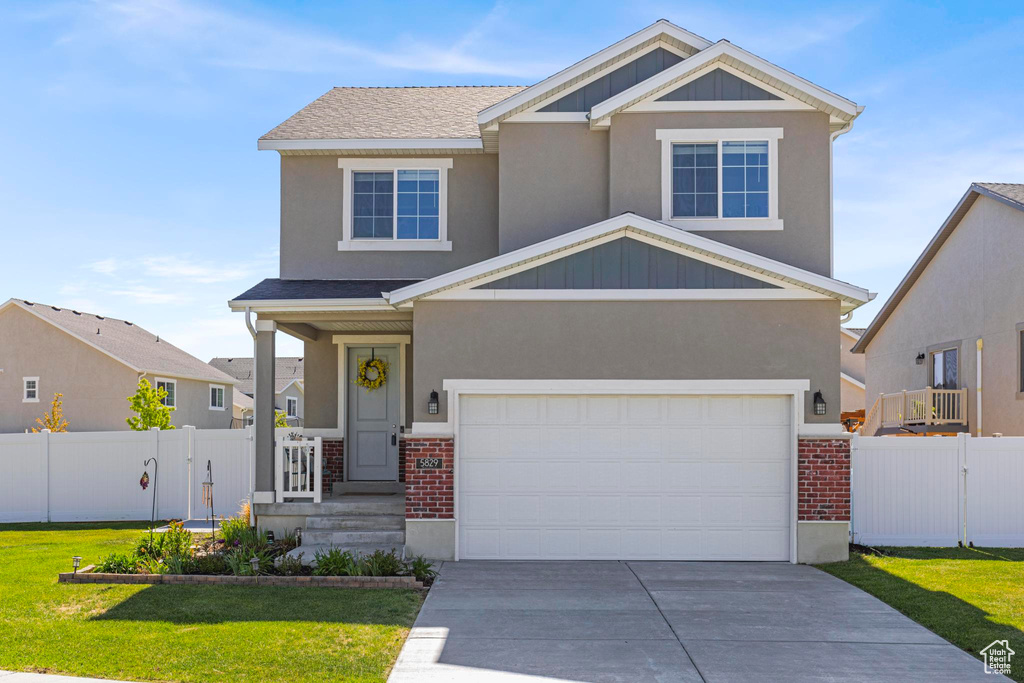 View of front of home featuring a garage, a front lawn, fence, brick siding, and concrete driveway
