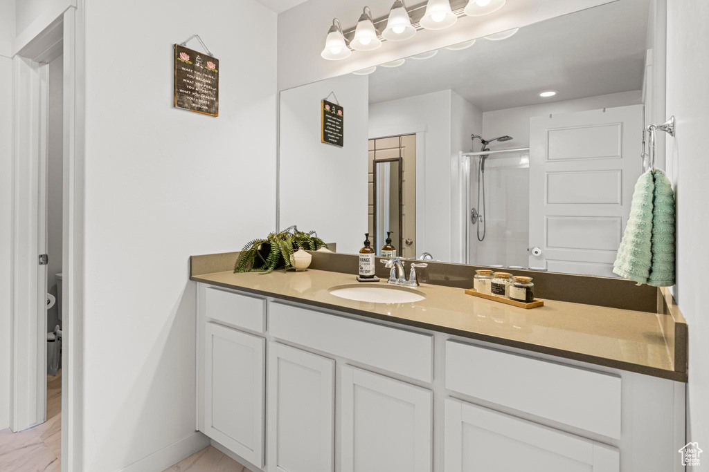 Full bathroom with vanity, baseboards, a stall shower, and marble finish floor