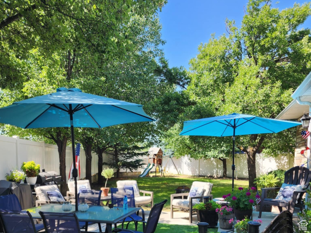 View of patio featuring outdoor dining area, a fenced backyard, and a playground