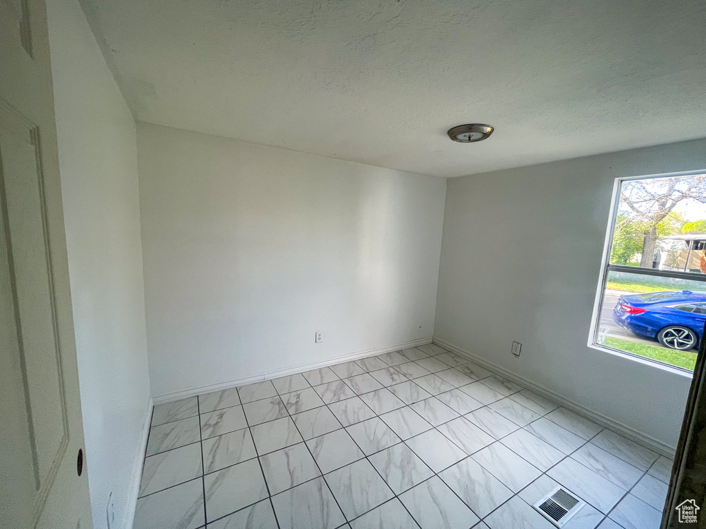 Unfurnished room featuring a textured ceiling, baseboards, visible vents, and marble finish floor