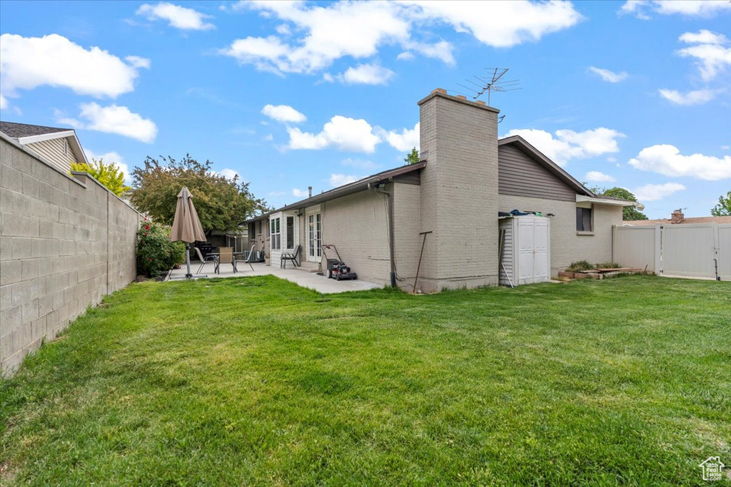 Rear view of property featuring a patio, a chimney, brick siding, and a gate