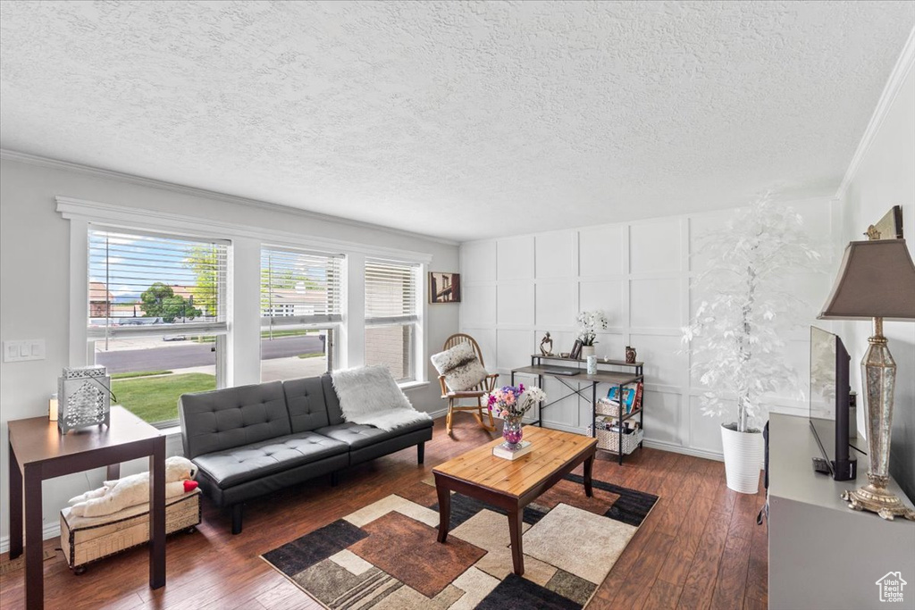 Living area featuring hardwood / wood-style flooring, a decorative wall, a textured ceiling, and crown molding
