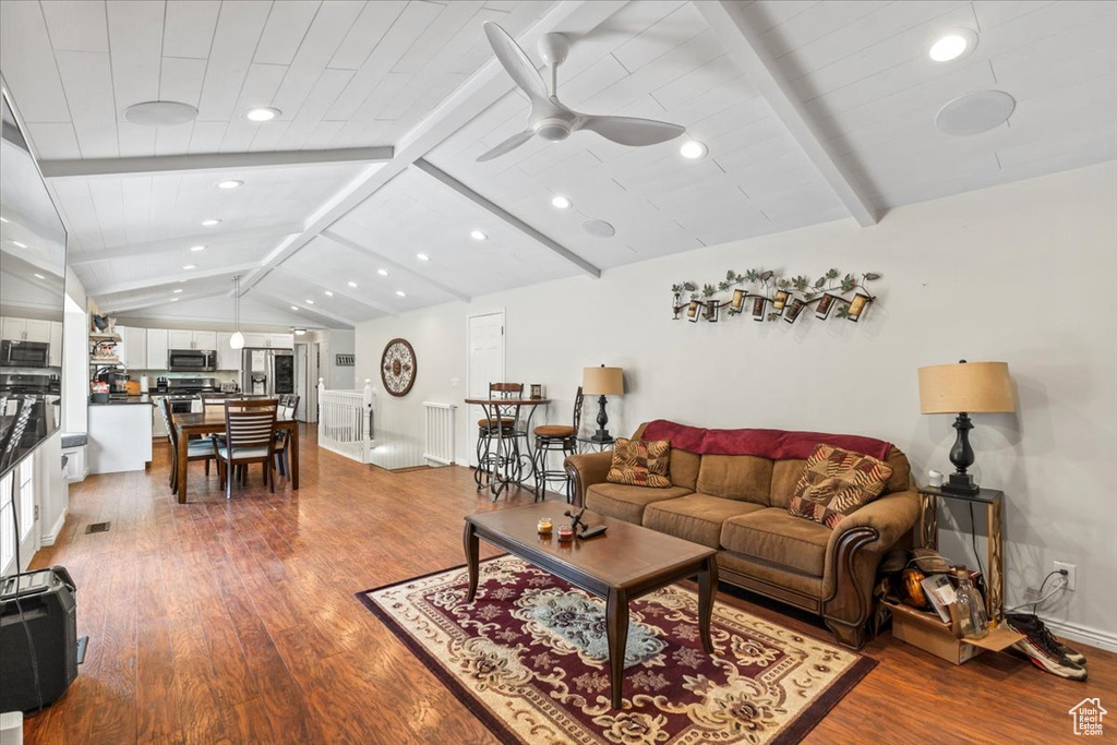 Living area with dark wood-type flooring, ceiling fan, and baseboards