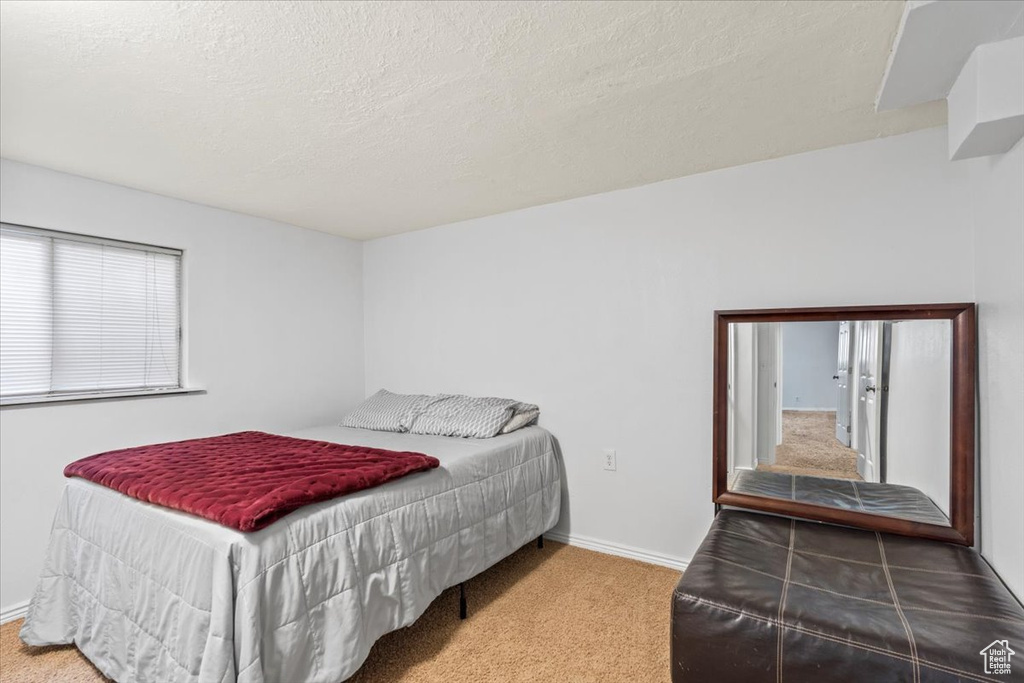 Carpeted bedroom featuring a textured ceiling and baseboards