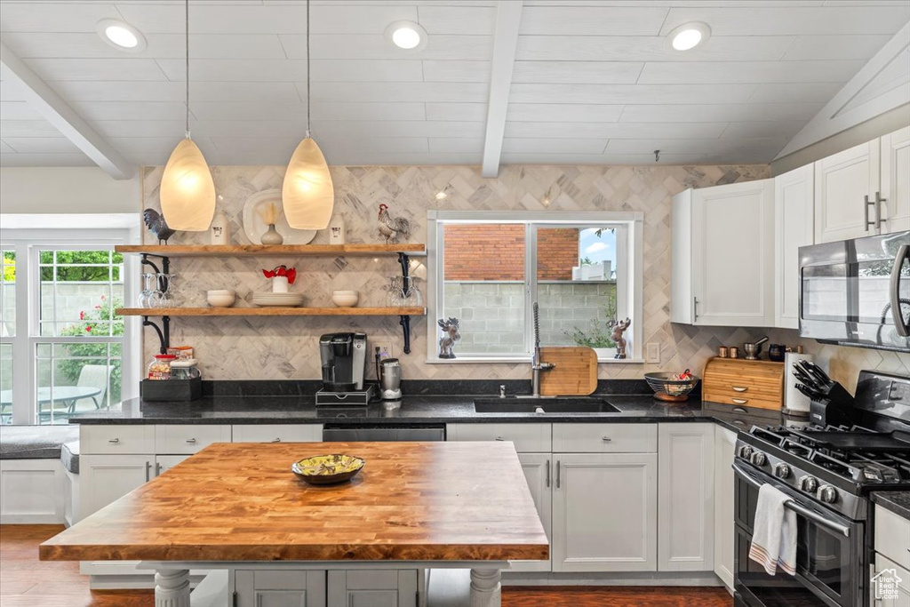 Kitchen with double oven range, a sink, dark wood-style floors, decorative backsplash, and beamed ceiling