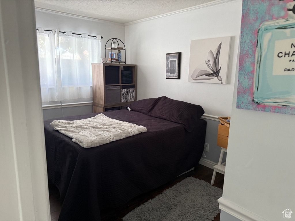 Bedroom with crown molding, a textured ceiling, and wood finished floors