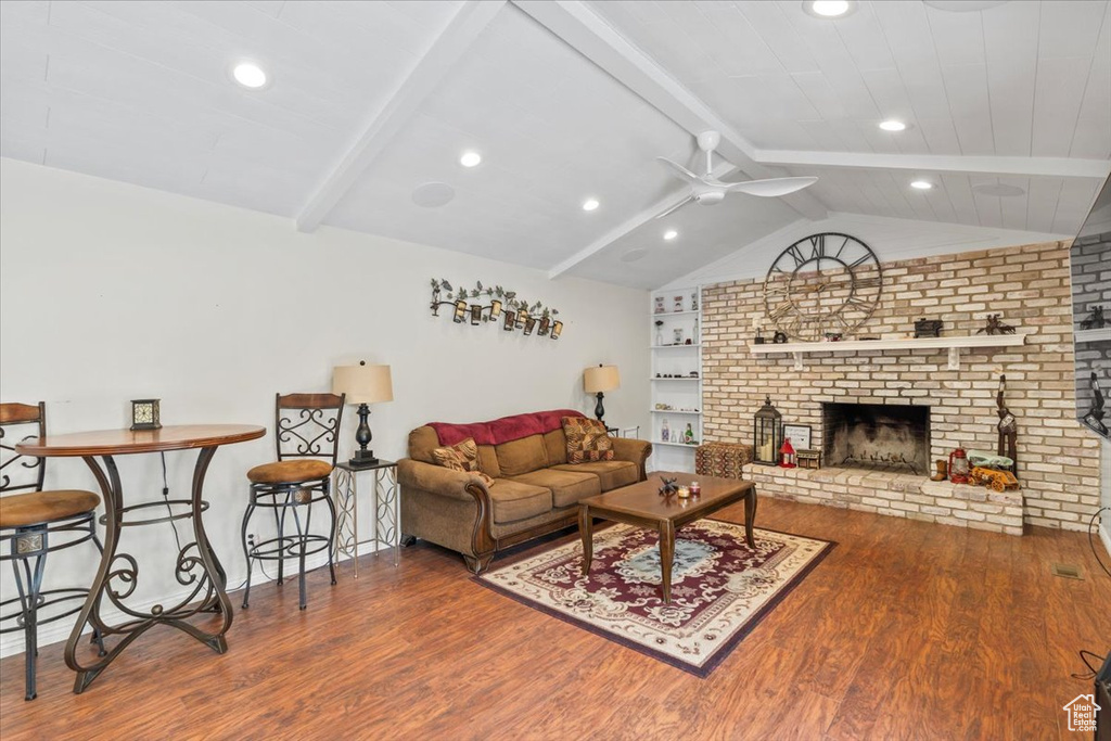 Living room featuring wood finished floors, ceiling fan, recessed lighting, and a fireplace