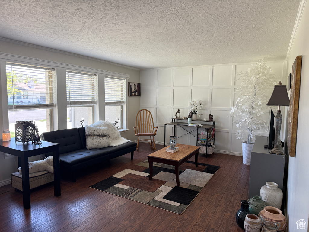 Living area with dark wood-style flooring, a textured ceiling, and a decorative wall