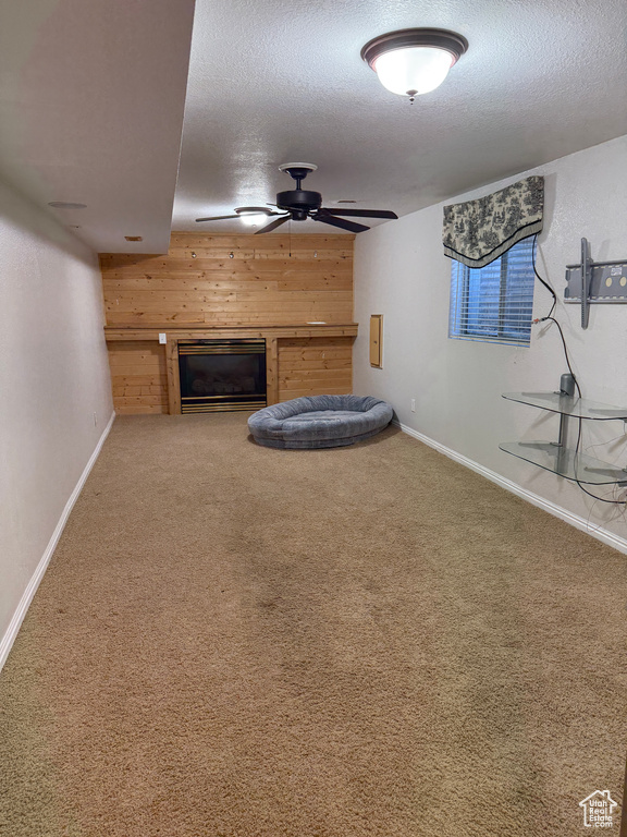 Unfurnished living room featuring a glass covered fireplace, carpet flooring, and wood walls