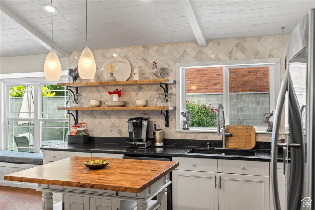 Kitchen featuring a sink, stainless steel appliances, butcher block countertops, tasteful backsplash, and beam ceiling