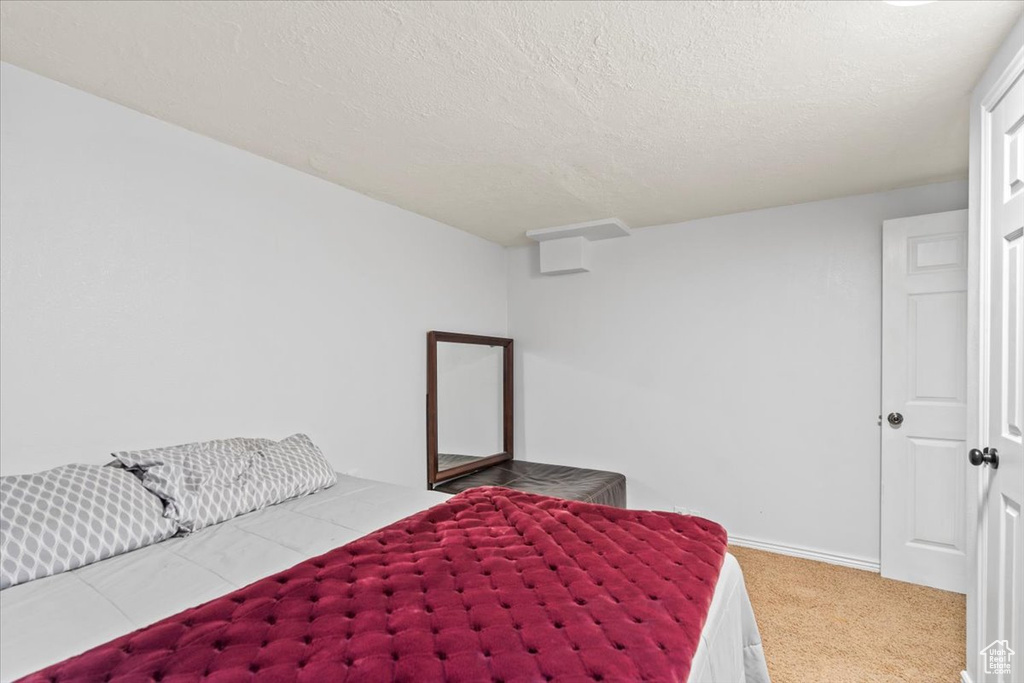 Bedroom with a textured ceiling, carpet floors, and baseboards