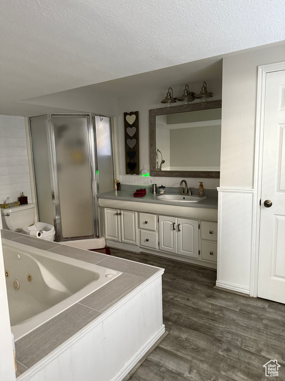 Bathroom featuring vanity, wood finished floors, a tub with jets, a textured ceiling, and an enclosed shower