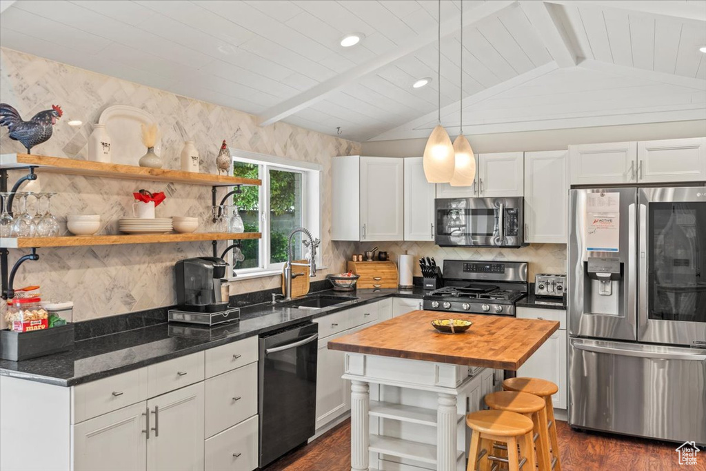 Kitchen featuring appliances with stainless steel finishes, a sink, open shelves, wood counters, and dark wood-type flooring