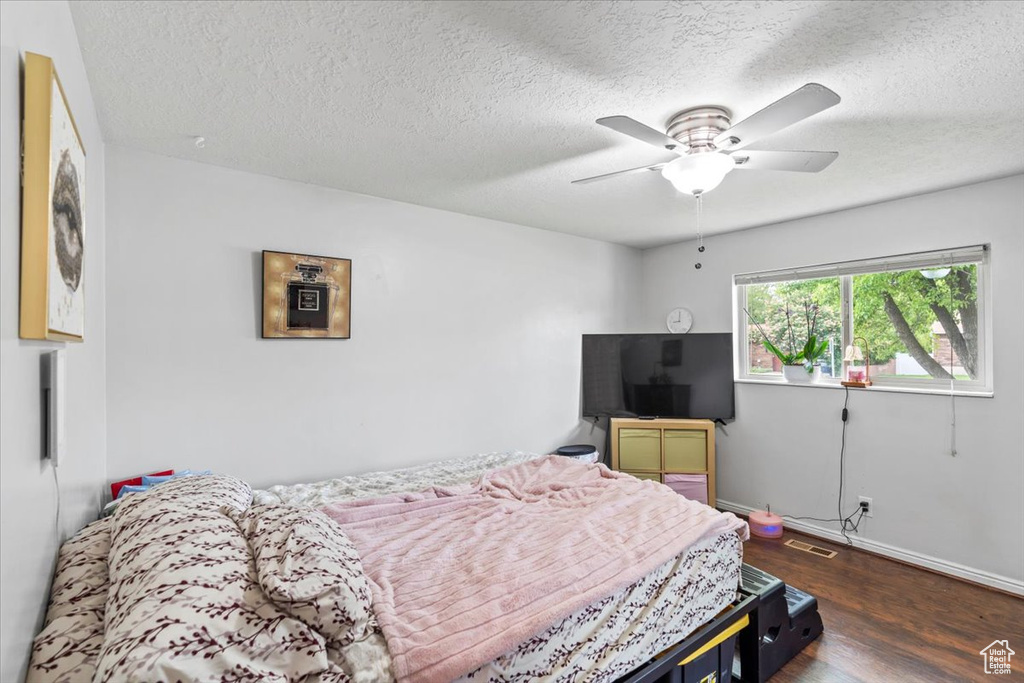 Bedroom featuring dark wood-type flooring, a textured ceiling, baseboards, and ceiling fan