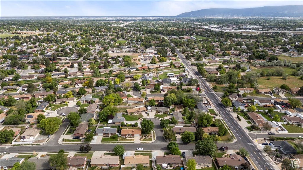Aerial view of property and surrounding area featuring mountains and nearby suburban area