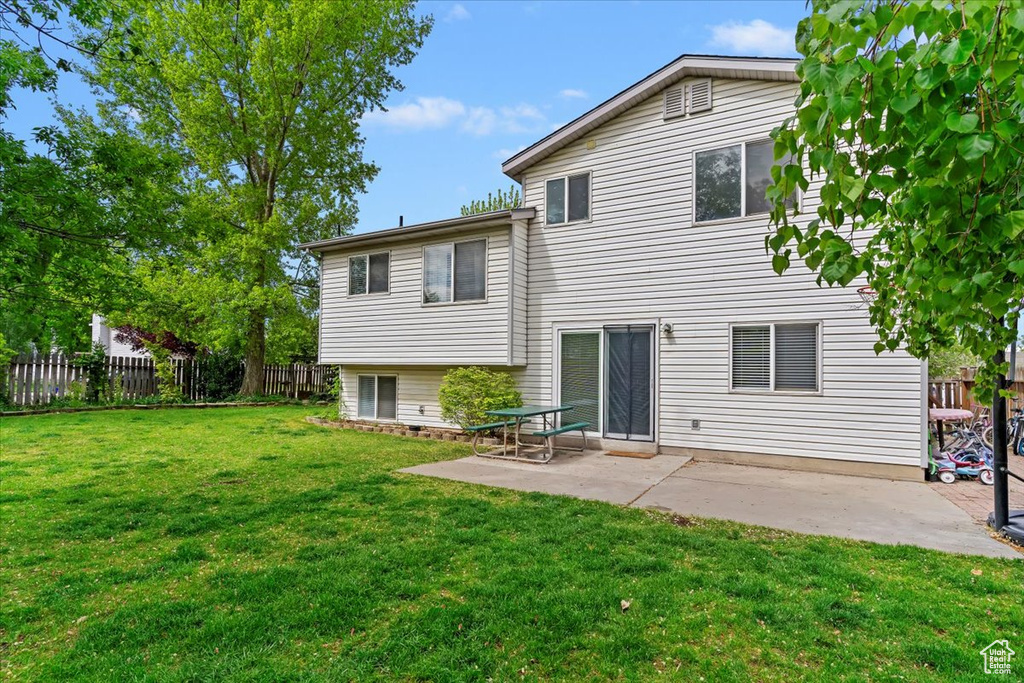 Rear view of house featuring a lawn, a patio area, and fence