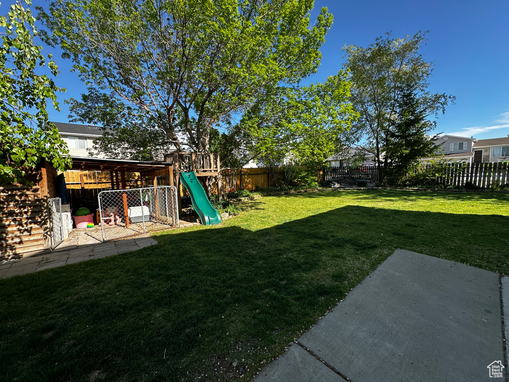 View of yard featuring a fenced backyard, a playground, and a patio area