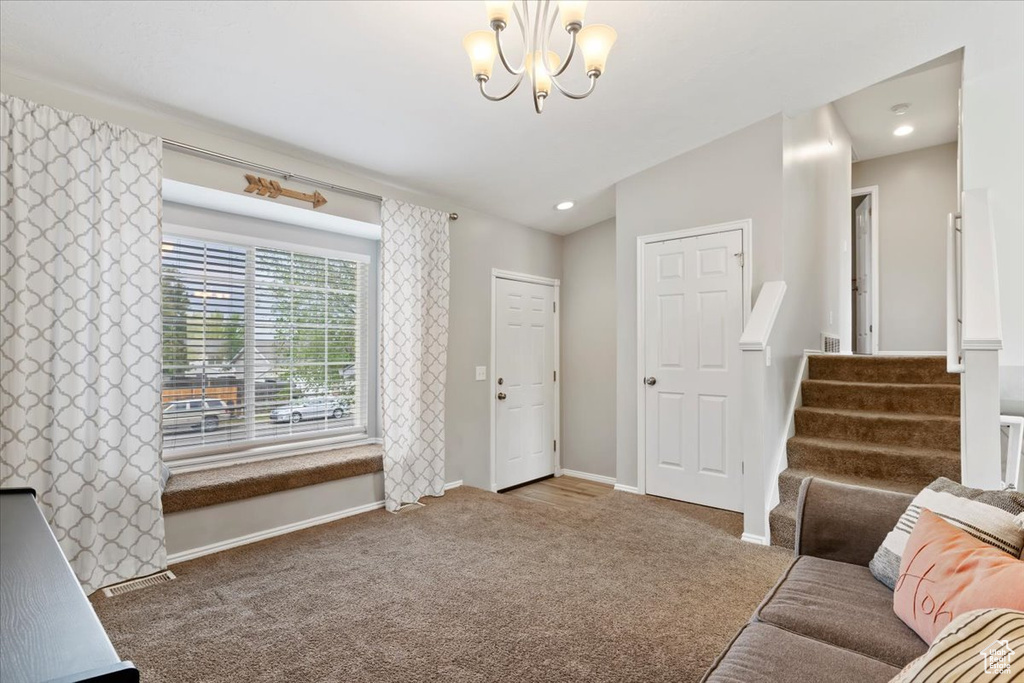 Carpeted living area featuring baseboards, stairs, a chandelier, and recessed lighting