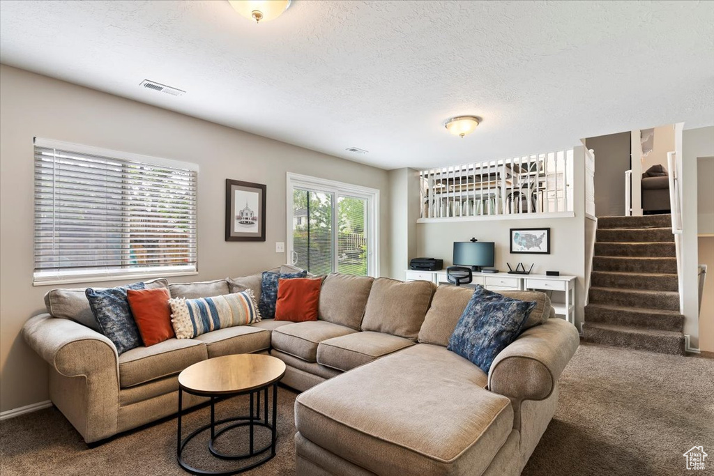 Carpeted living area with stairway, built in study area, a textured ceiling, and visible vents