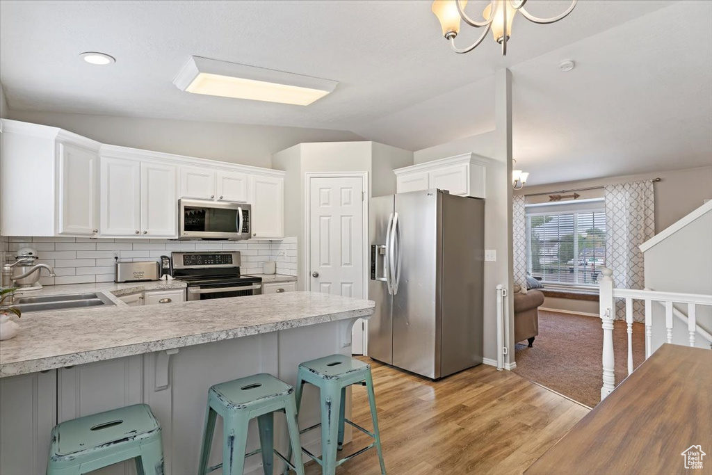 Kitchen with a sink, vaulted ceiling, stainless steel appliances, and light countertops