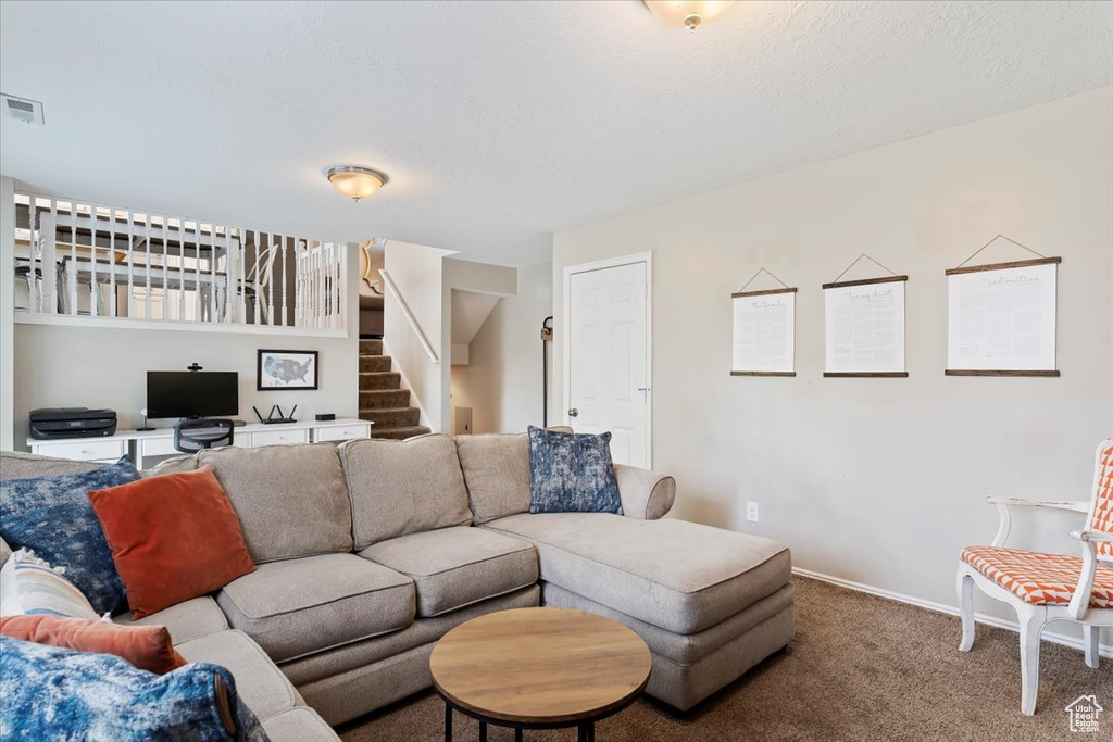 Living room with carpet, visible vents, baseboards, and stairs