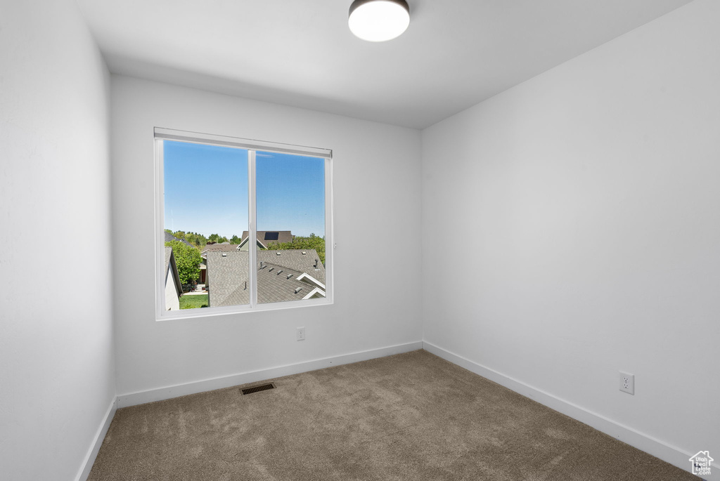Carpeted spare room with visible vents and baseboards