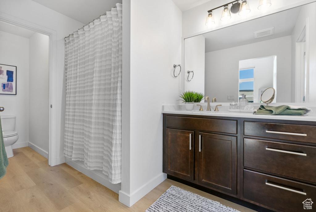 Bathroom featuring vanity, toilet, wood finished floors, and visible vents