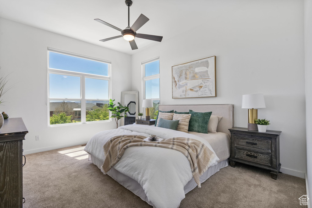Bedroom featuring a ceiling fan, baseboards, and light colored carpet