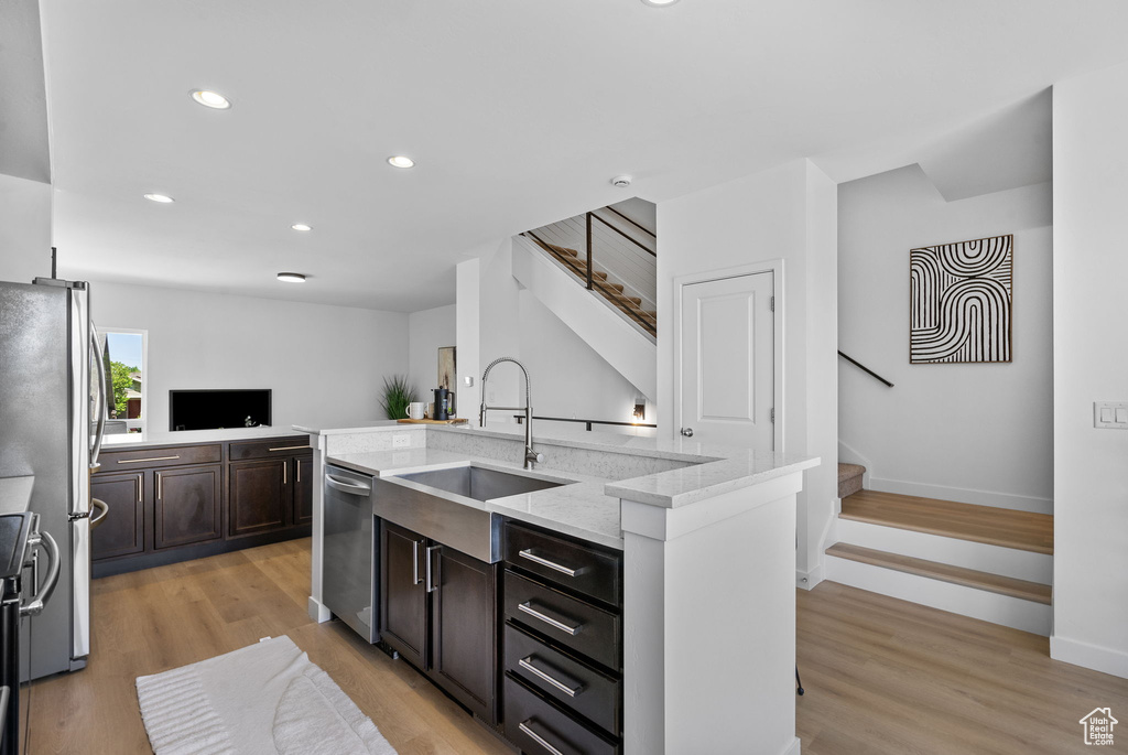 Kitchen with dark brown cabinets, an island with sink, recessed lighting, a sink, and stainless steel appliances