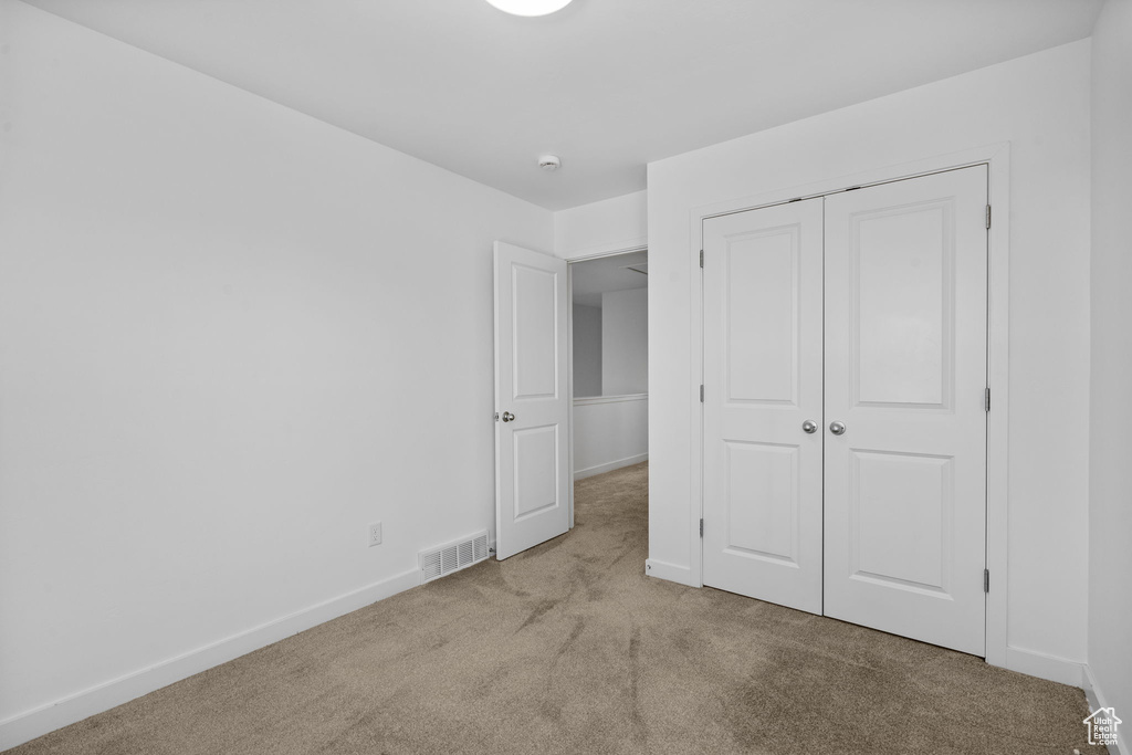 Unfurnished bedroom with baseboards, visible vents, carpet, and a closet
