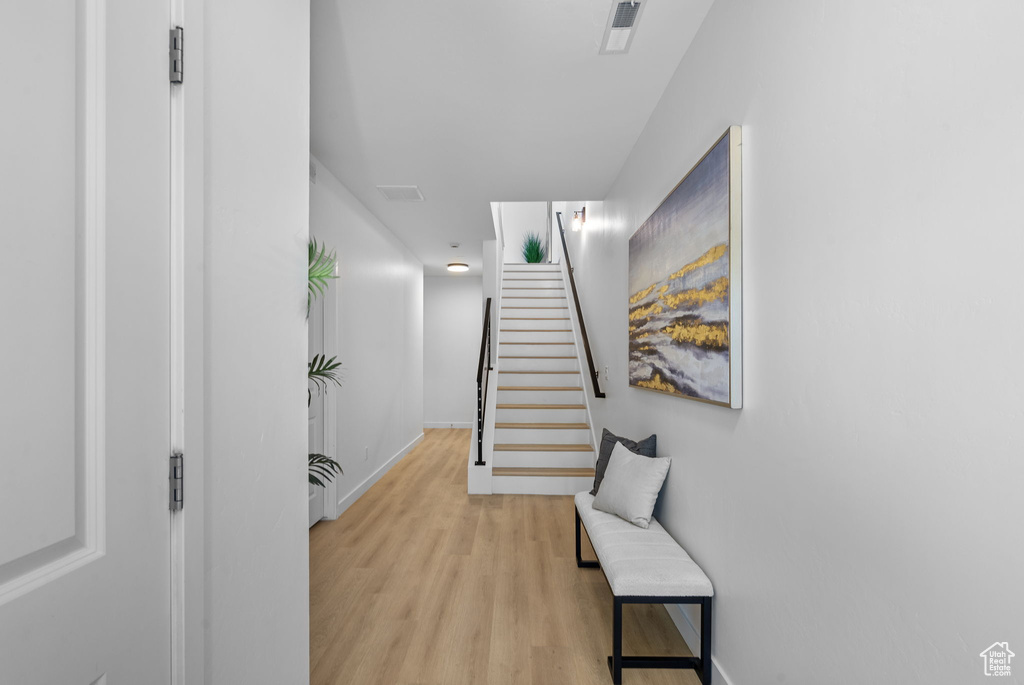 Corridor with light wood-style floors, baseboards, and stairs
