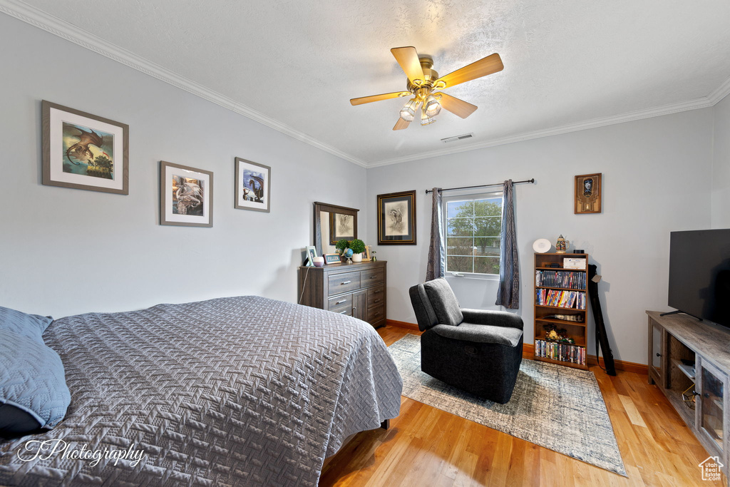 Bedroom featuring crown molding, ceiling fan, light wood-style floors, baseboards, and visible vents