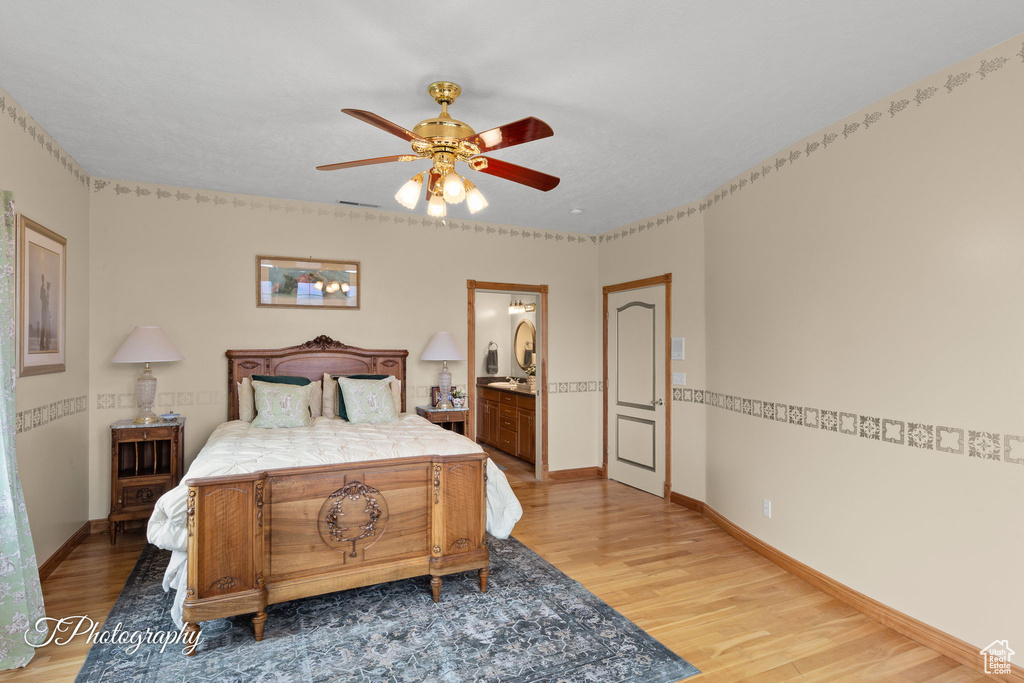 Bedroom with visible vents, baseboards, ceiling fan, light wood-style flooring, and ensuite bath