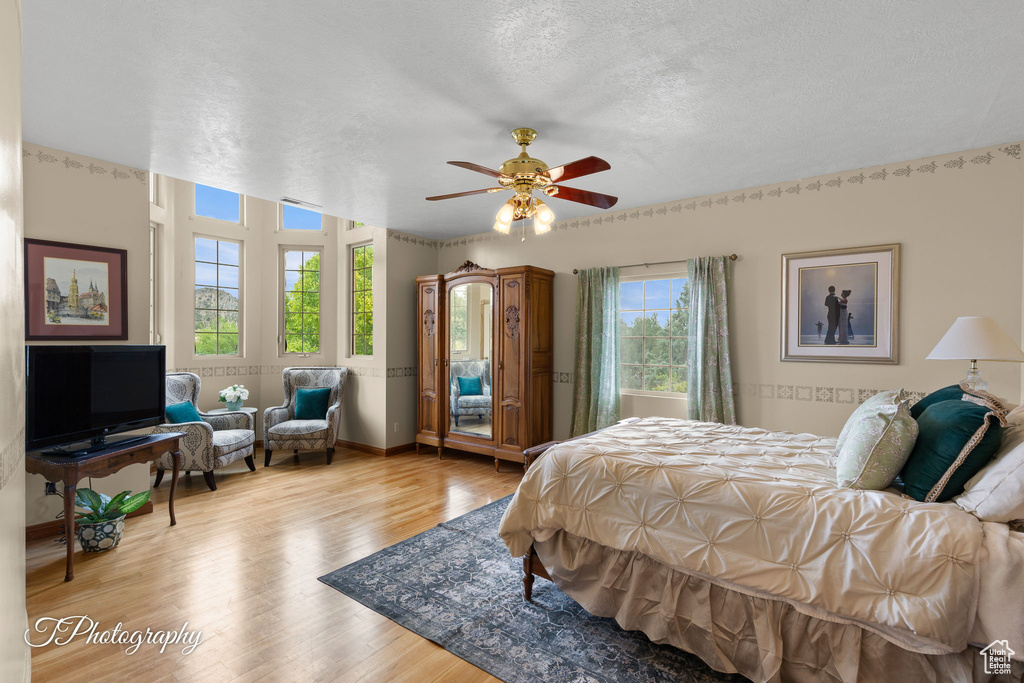 Bedroom with a textured ceiling, ceiling fan, and wood finished floors