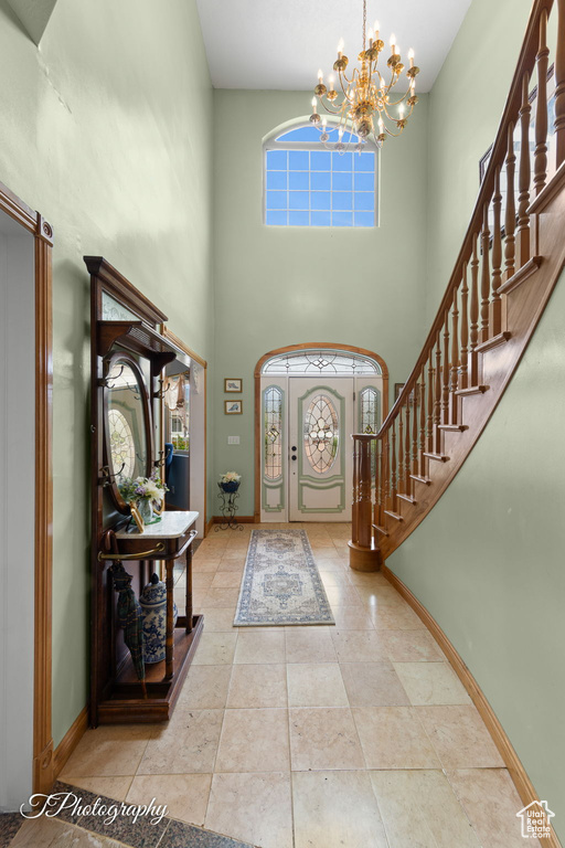 Entryway with baseboards, stairs, a towering ceiling, and a chandelier