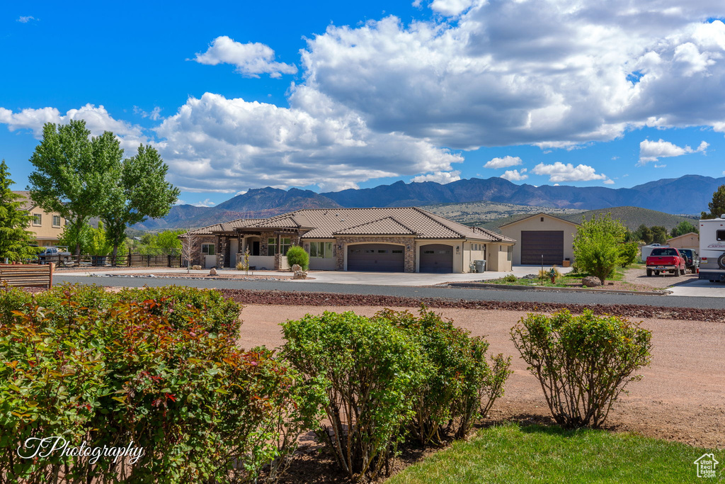 View of front of home with fence, an attached garage, a mountain view, a tiled roof, and driveway