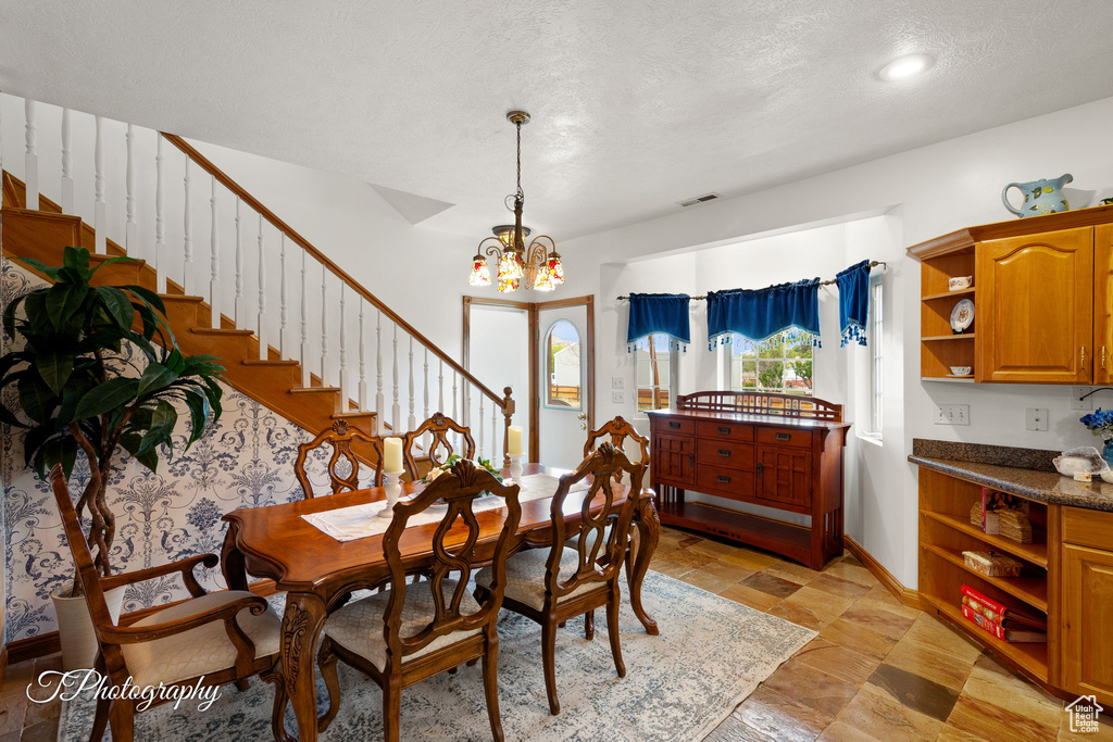 Dining area with an inviting chandelier, baseboards, visible vents, and stairway