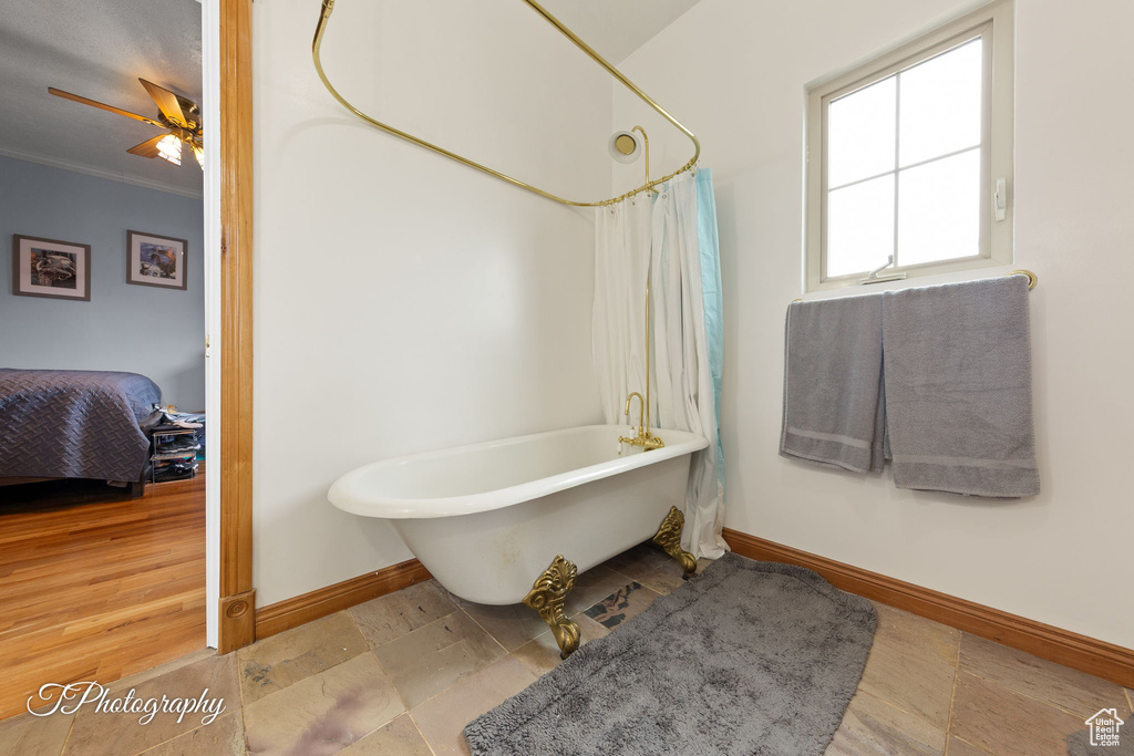 Ensuite bathroom with a shower with curtain, ceiling fan, baseboards, ornamental molding, and a soaking tub